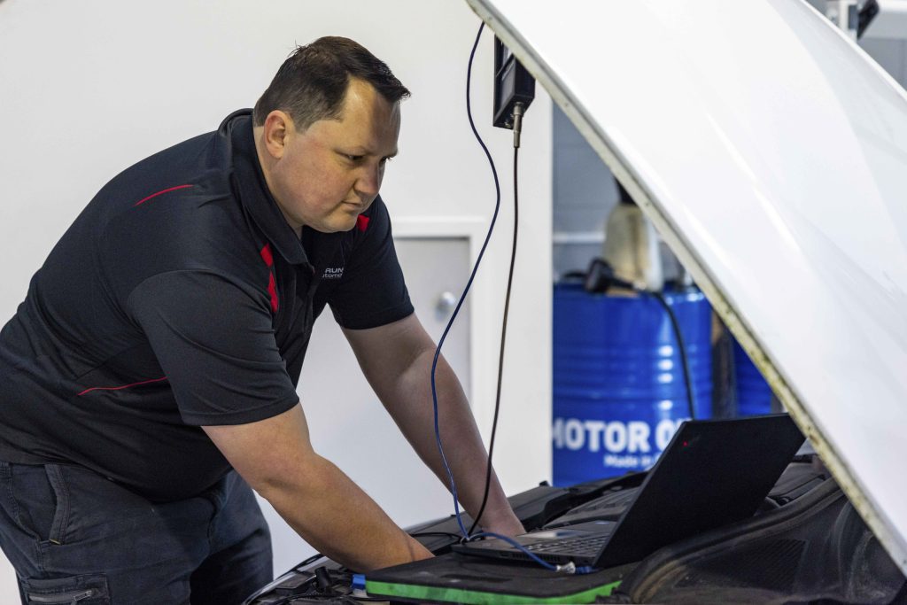 Mechanic using diagnostic equipment to check a diesel, hybrid and electric European car during a logbook service in Auckland