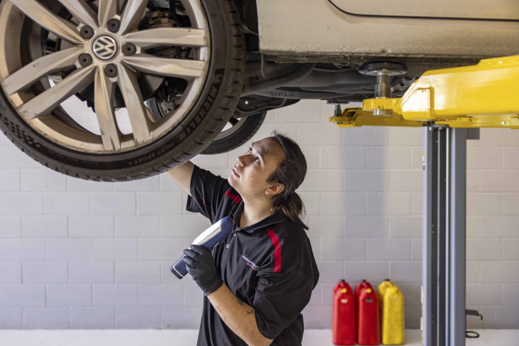 Technician inspecting the underside of a European car on a hoist
